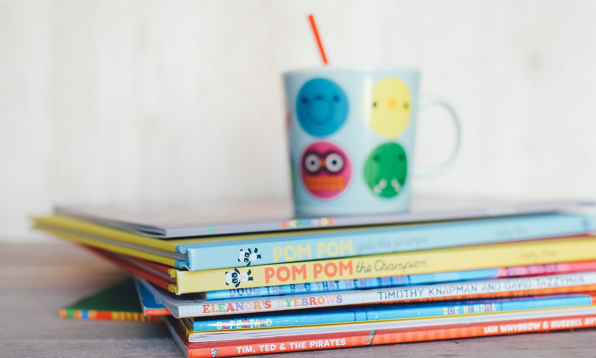 a photo of children's books and a mug in matching colors to promote the friends of The Santa Clara City Library book sale at Northside library