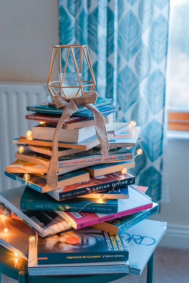 a lovely blue photo of a Christmas tree made of books to advertise the November monthly book sale held by The Santa Clara City library foundation and friends