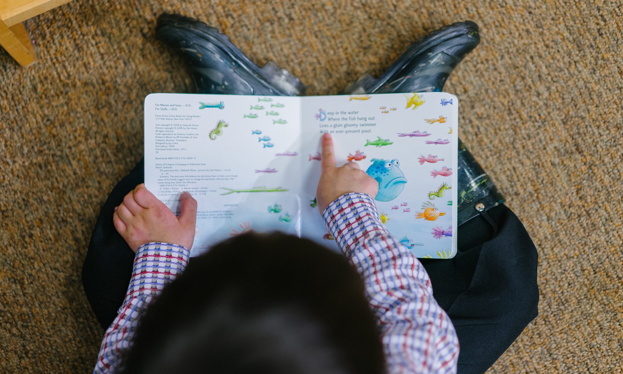 photo of a child reading a board book to advertise the back-to-school book sale at Northside Library