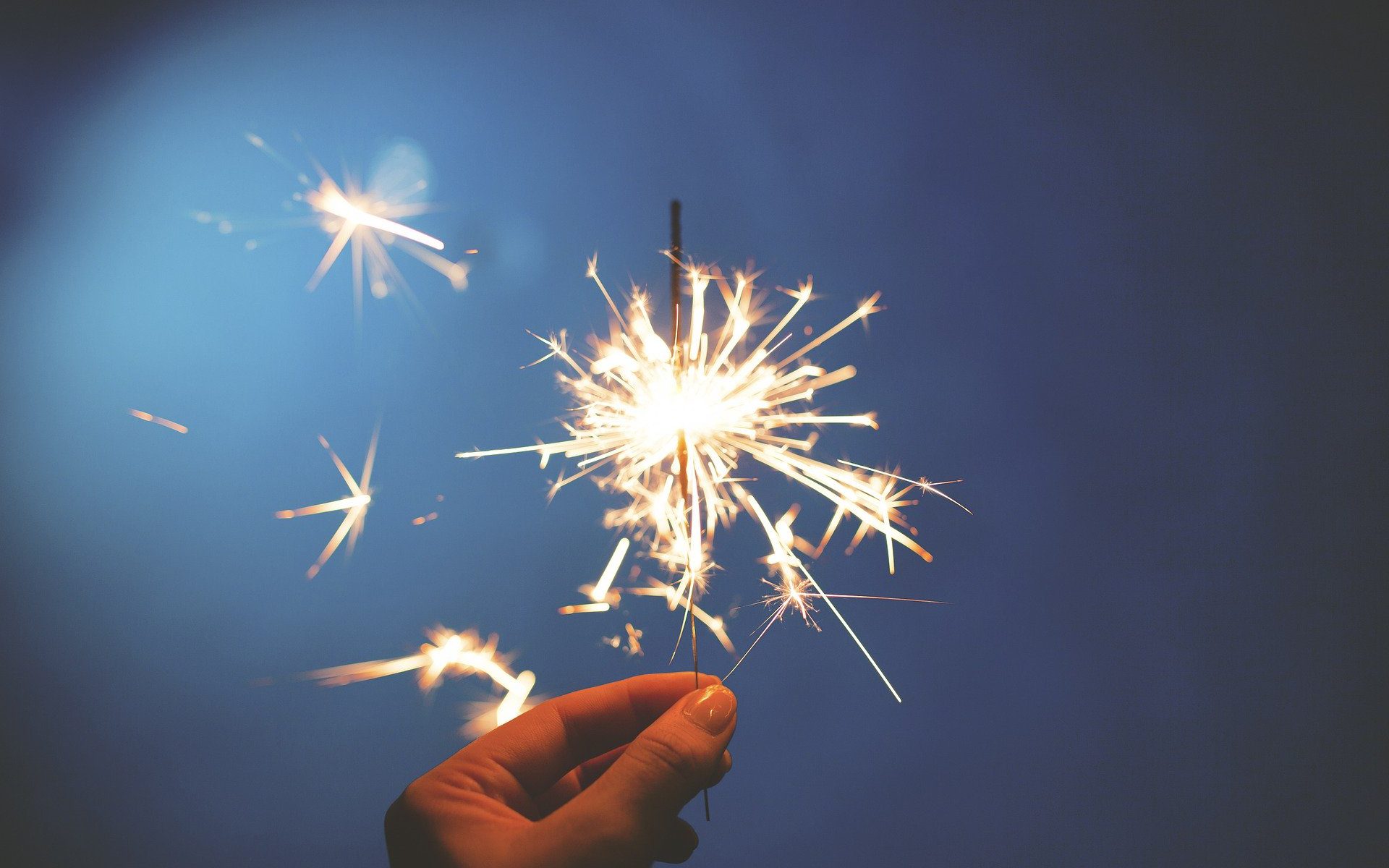 a photo of a hand holding a sparkler to wish everyone a happy new year from the santa Clara city library foundation and friends