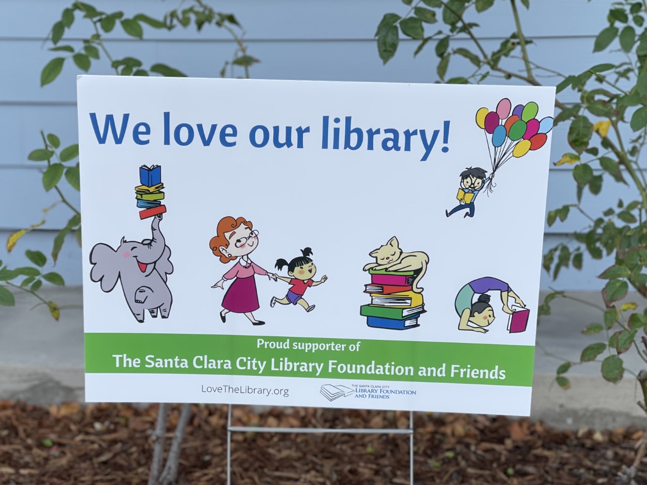 A photo of the "we love our library" yard sign supporting The Santa Clara City Library foundation and friends