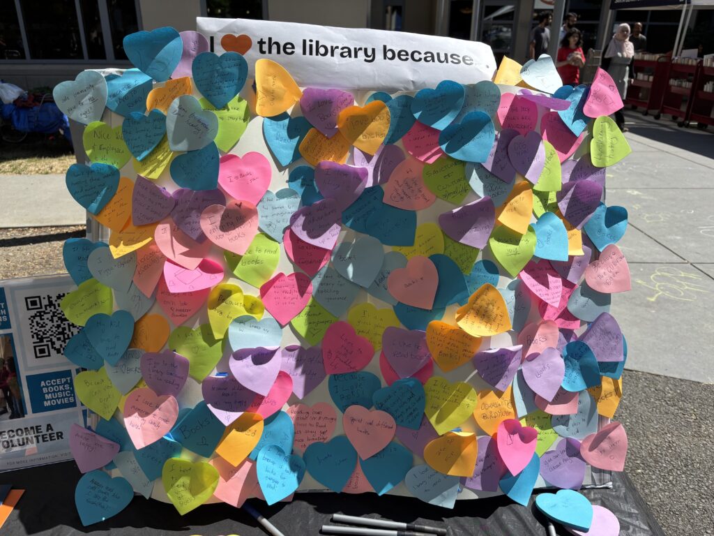 A board full of colorful paper hearts that read "I love the library because..." at the top.